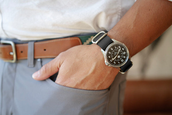 Closeup of a man's hand in his pocket. He is wearing a Wasson Automatic Field Watch with black nato strap.
