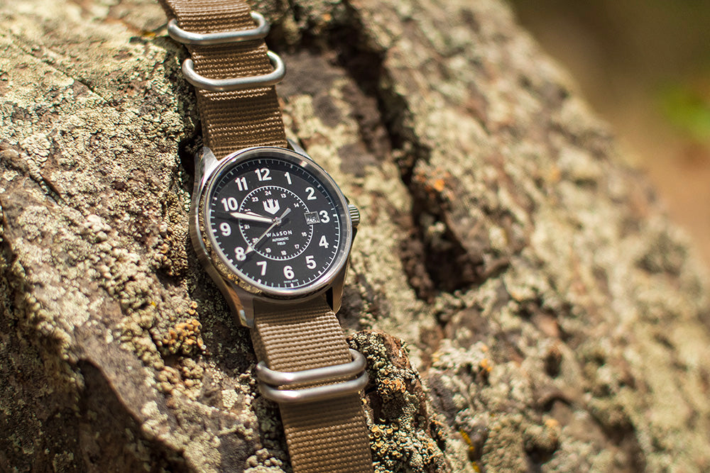 Wasson Automatic Field Watch with khaki nato strap is laid over a textured rock.