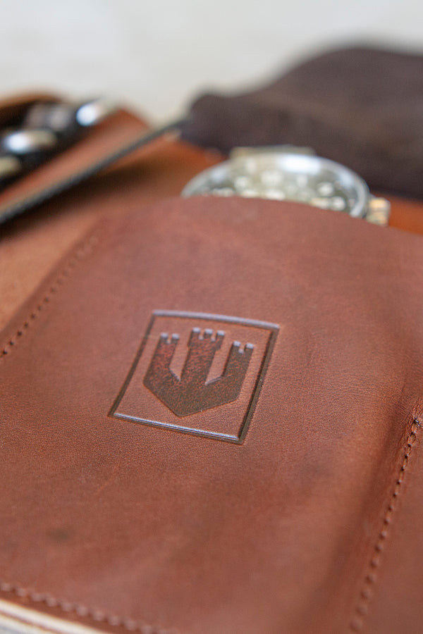 Close up of an interior pouch of the leather tool roll. The stainless steel automatic field watch is in the pocket of the tool roll. The Wasson logo is stamped on the exterior of the pocket.