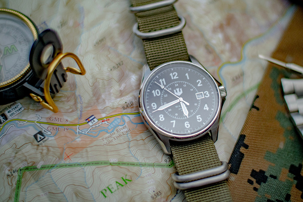 Swiss Made Automatic Field Watch with green nato strap is laid out on a map with a compass to the side.